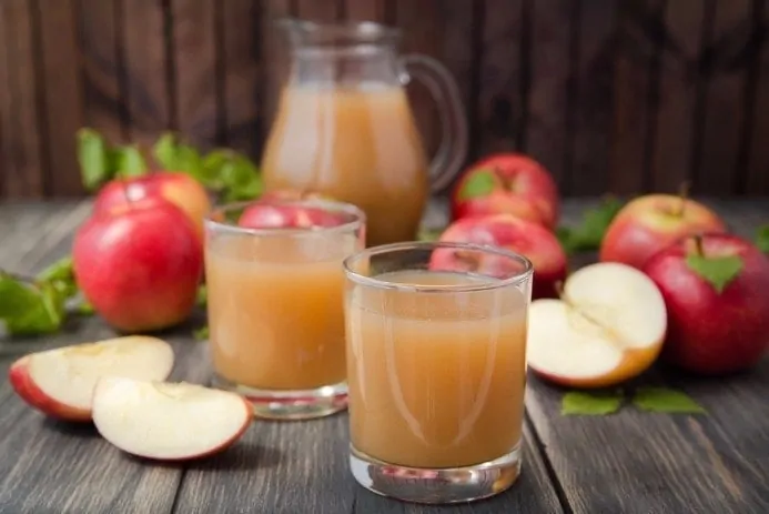 Suco detox de maçã em copos, com maçãs inteiras e cortadas ao redor.
