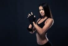 Quais são os Anabolizantes mais Usados pelas Mulheres? Mulher fitness com luvas de treino, vestindo roupa esportiva preta.