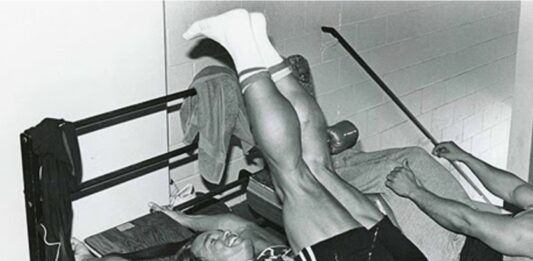 Treino de Abdômen do Arnold Schwarzenegger (Avançado) Homem fazendo exercício avançado de abdômen com peso na academia.