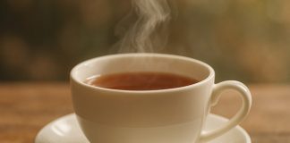Melhores Chás para Dormir de fácil preparo que prometem ajudar você a Dormir Melhor Xícara de chá quente em uma mesa de madeira.