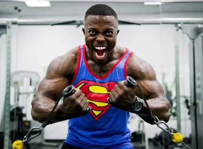 Homem musculoso treinando força com resistência na academia.