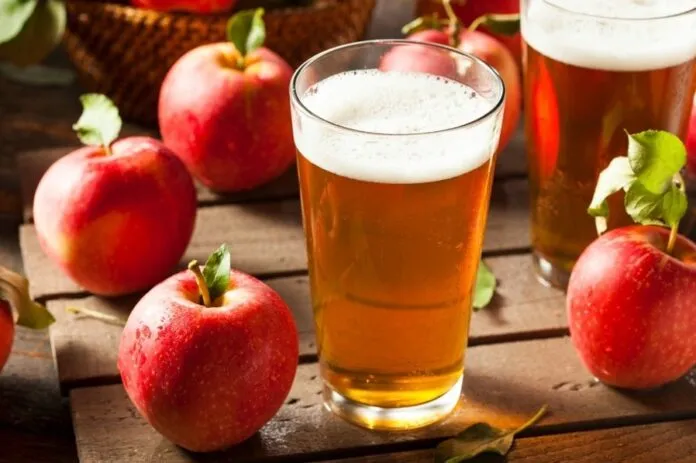 Copo de sidra de maçã natural Sidra de maçã natural com maçãs frescas ao redor.