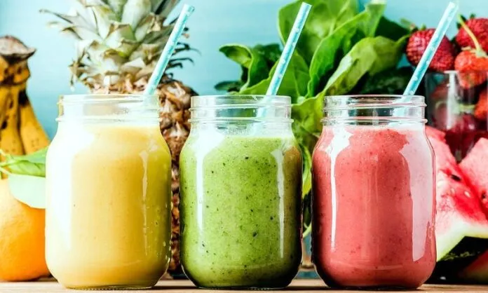 Smoothies de frutas e vegetais frescos Três smoothies coloridos de frutas e vegetais em potes de vidro com canudos.