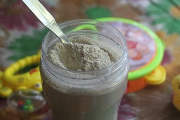 Suplemento de proteína em pó para crianças Pó de proteína em um copo com colher, ideal para crianças e lactantes.