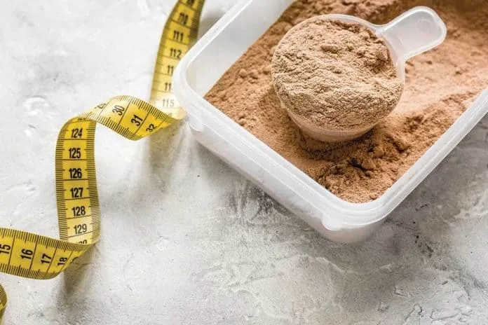 Proteína em pó e fita métrica para ganho de massa muscular.