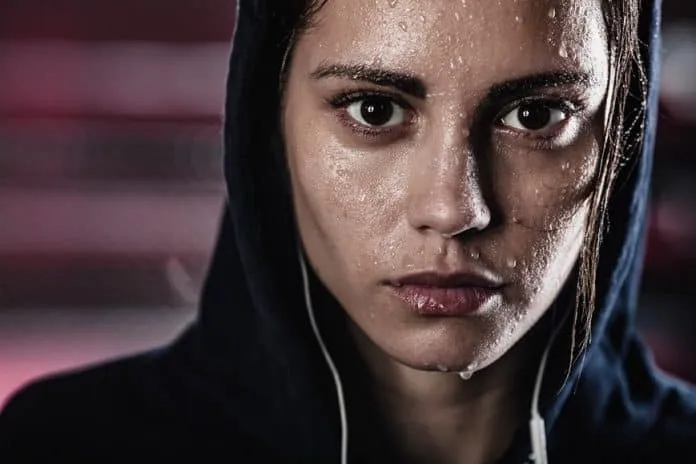 Mulher suando após treino intenso Mulher com expressão determinada, suando após exercício físico intenso.
