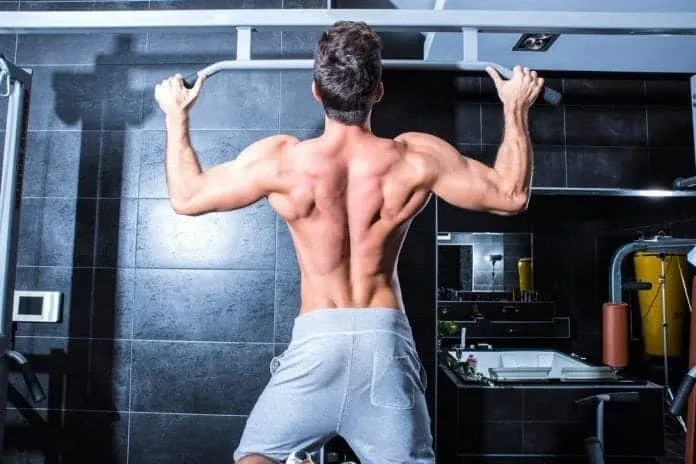 Exercício de barra fixa para força Homem fazendo barra fixa na academia para treinar costas e braços.