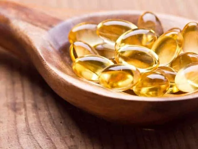 Capsulas de vitamina D em colher de madeira, promovendo saúde óssea e imunidade.