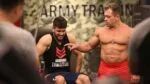 Fernando Sardinha treinando com jovem atleta em academia de fisiculturismo.