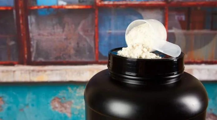 Whey Protein em Pote Preto Pote de whey protein com colher medidora em fundo colorido.
