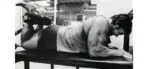 Arnold Schwarzenegger realizando exercício de pernas avançado.