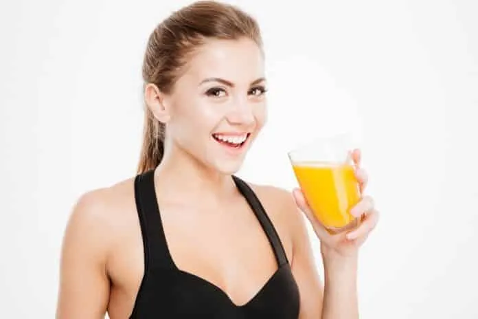 Mulher tomando suco de laranja Mulher sorridente segurando copo de suco de laranja.