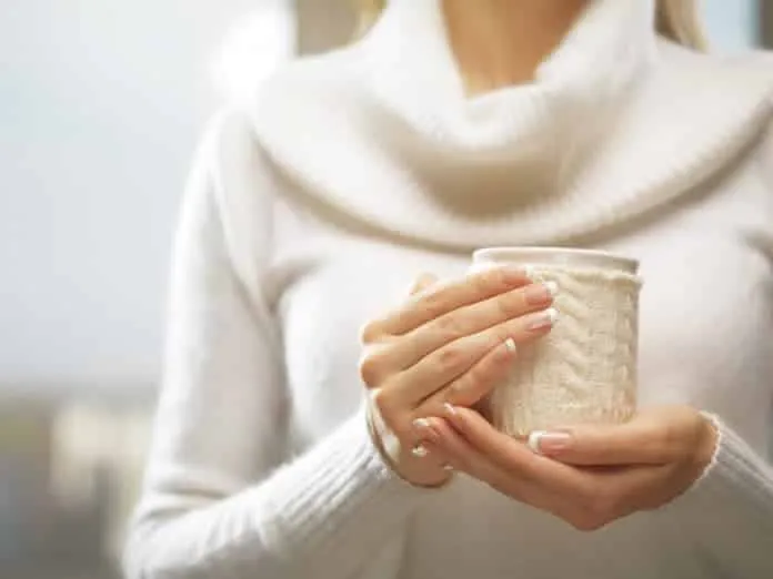 Homenagem ao Colágeno para Unhas Mulher segurando uma xícara de chá ou café com roupas de inverno.