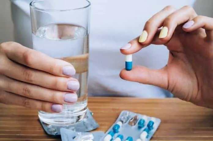 Uso de Cobamamida para anemia Pessoa segurando uma cápsula de Cobamamida e um copo de água.