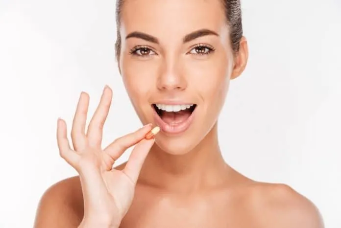 Mulher tomando suplemento de Inositol Mulher sorridente segurando suplemento de Inositol para saúde.