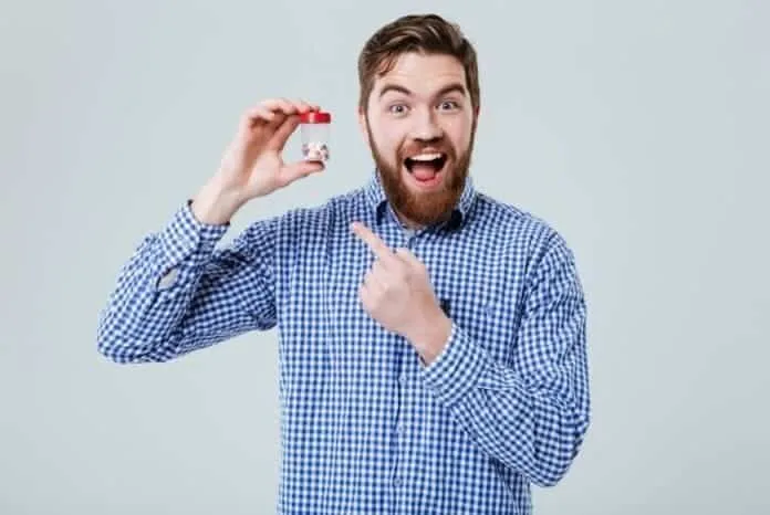 Homem com suplemento de Coenzima Q10 Homem feliz segurando suplemento de Coenzima Q10 para ganho muscular.