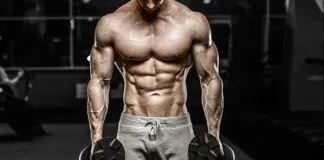 Homem musculoso treinando com halteres na academia.